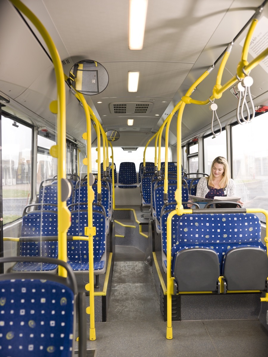 Woman reading a paper on an empty bus