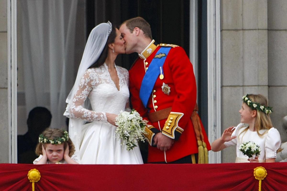 Prince William and his wife Kate Middleton kissing on the balcony of Buckingham Palace, London watched by bridesmaids Margarita Armstrong-Jones (right) and Grace Van Cutsem (left), following their wedding at Westminster Abbey in April 2011