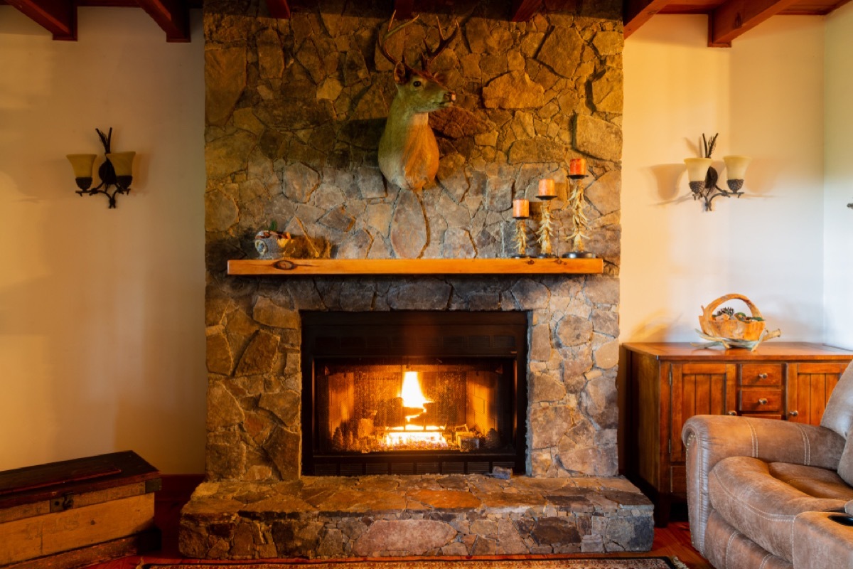 stone fireplace and wood mantle with deer head taxidermy