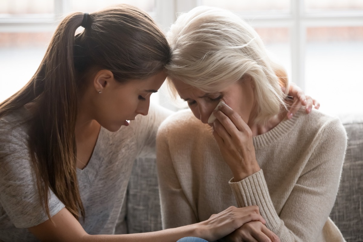 Grown up daughter soothe aged mother holds her hand feel empathy give her moral support elderly woman crying wipe tears with tissue, health problem disease, divorce broken heart adult child supporting.