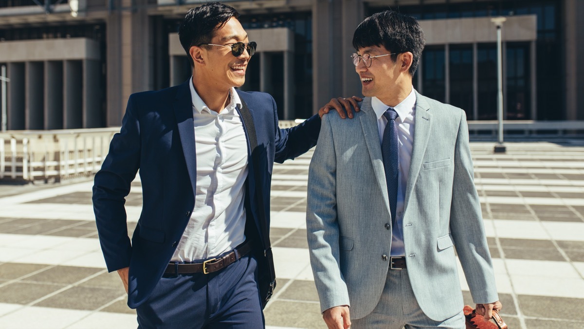 two businessmen walking out of work together while it is still light out