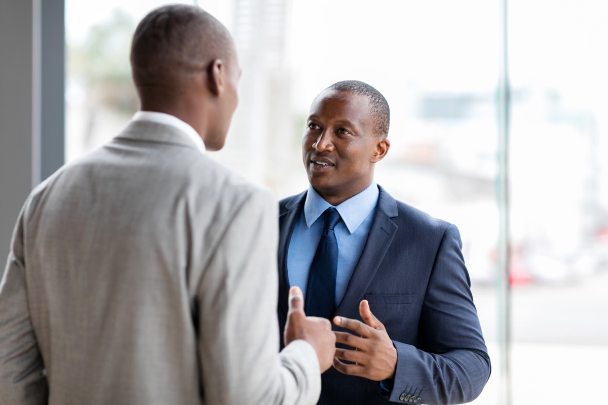 two middle aged black colleagues talking at work