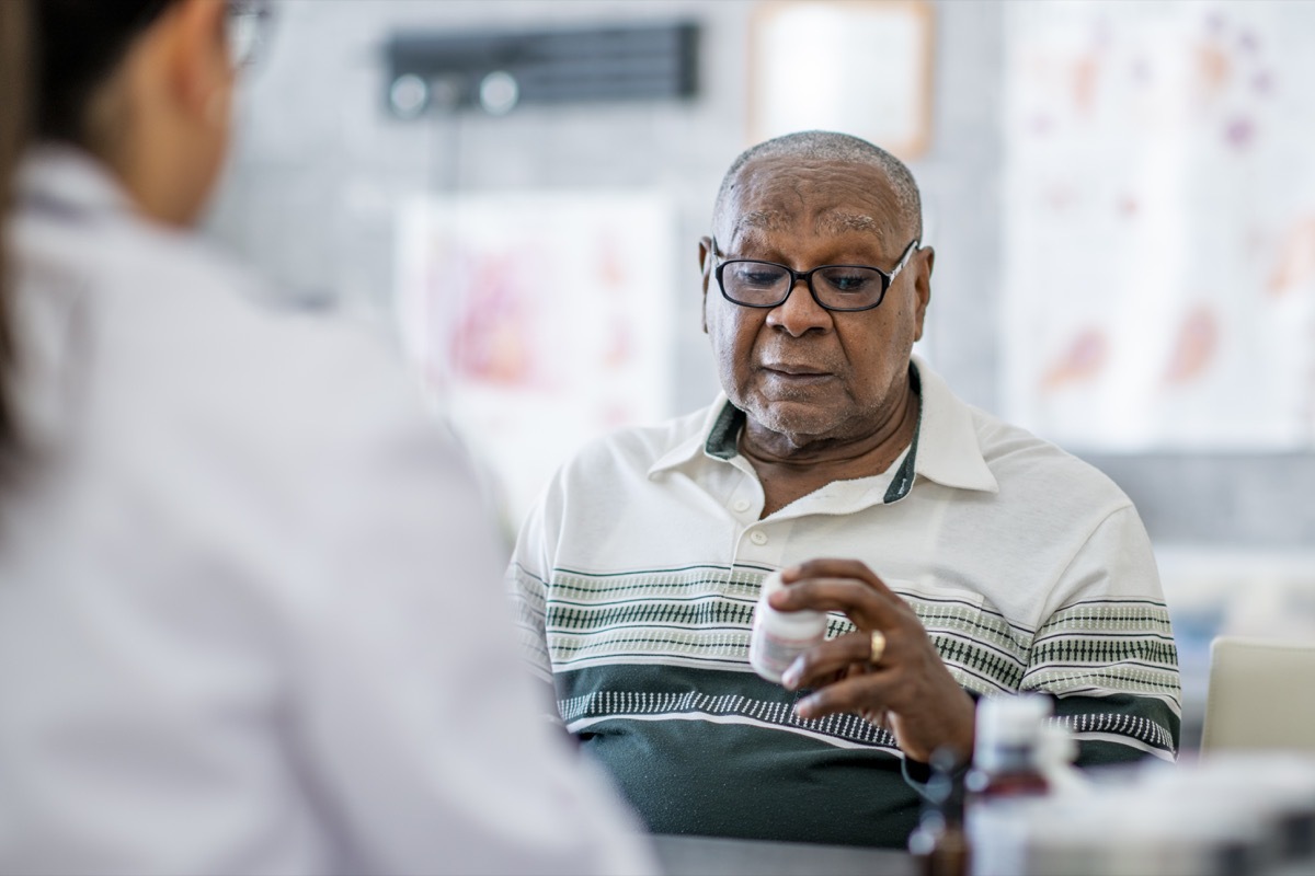 elderly man looking at a pill bottle the doctor just gave him