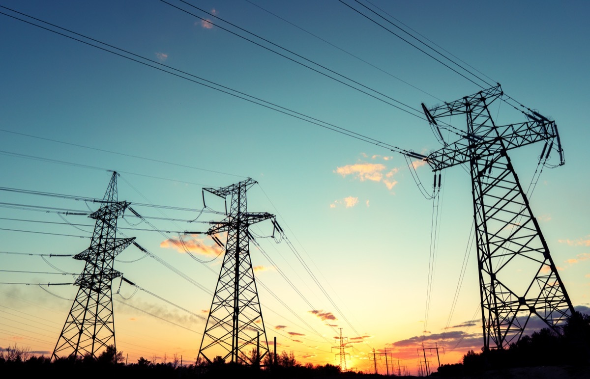 silhouette of high voltage power lines against a colorful sky at sunrise or sunset.