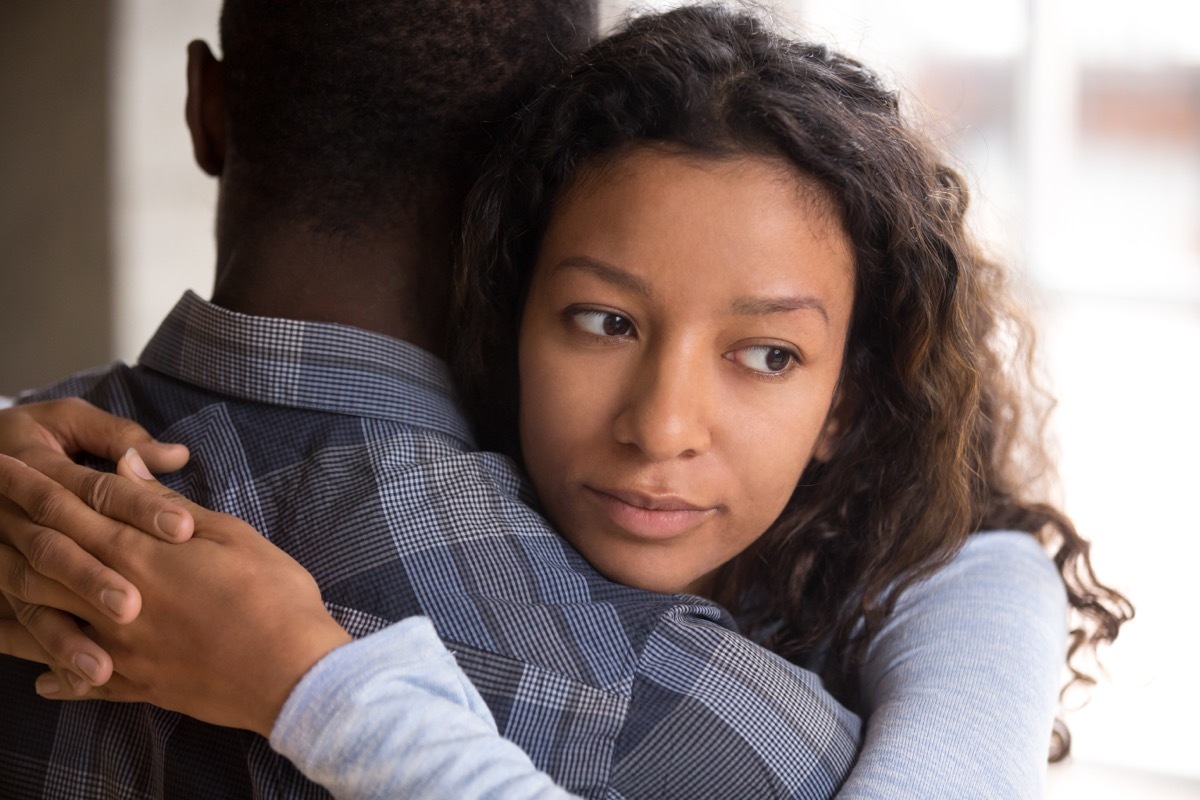 young black couple hugging, but woman looks doubtful