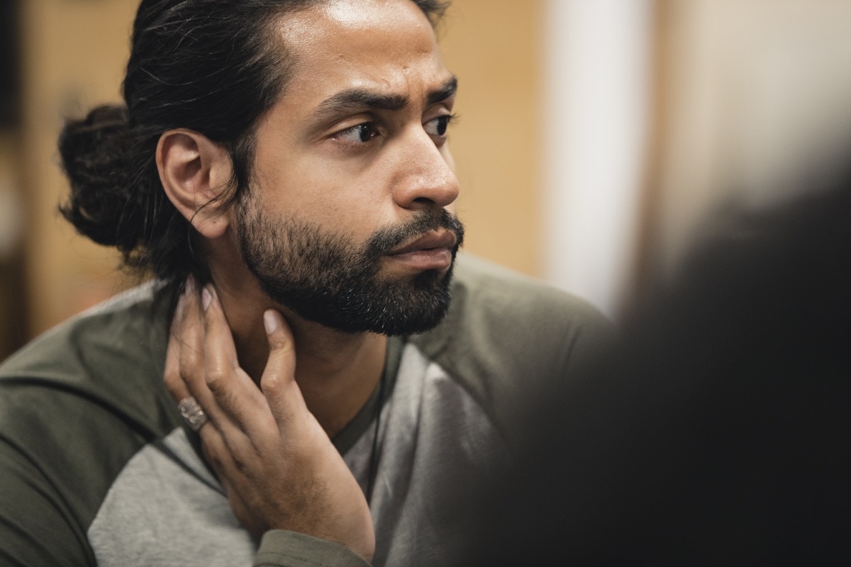 Close up shot of a mid-adult man listening to someone speaking whilst sitting in a support group session.