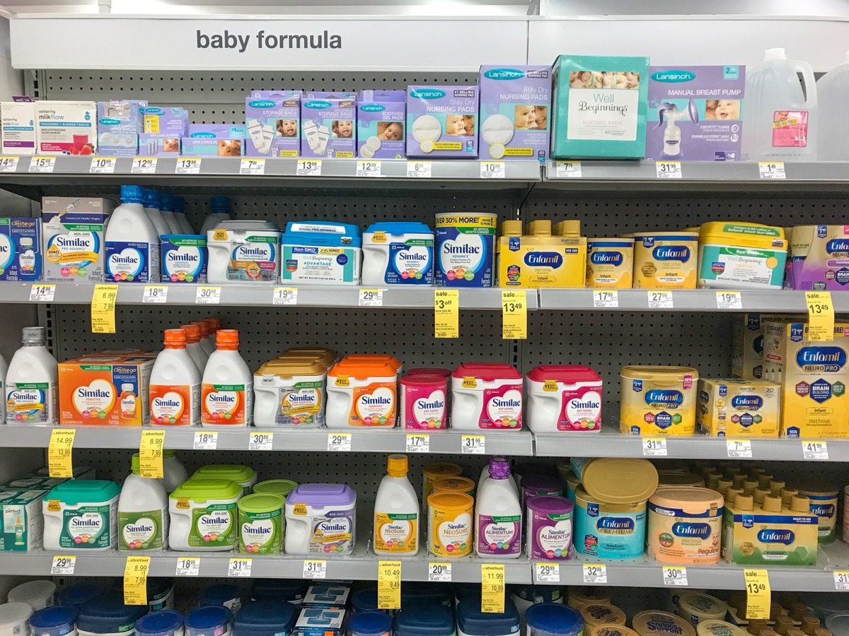 Various baby formula packages on the shelves of a Walgreens drug store.