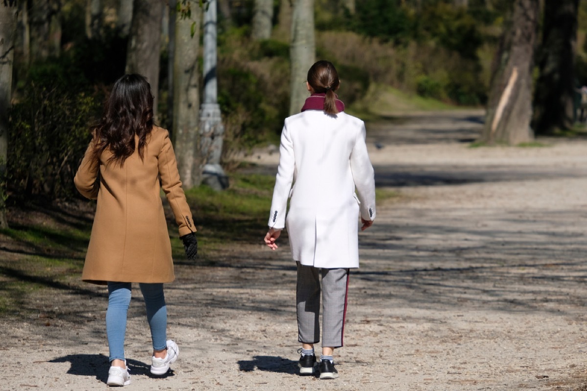 two women walking on a path from behind