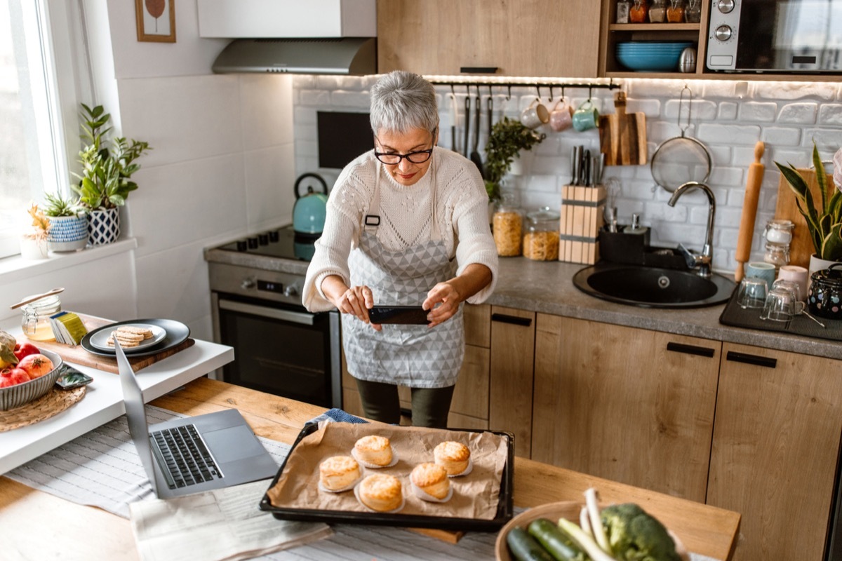 Mature woman taking a photo of baked pastries fresh out of oven, for her cooking blog.