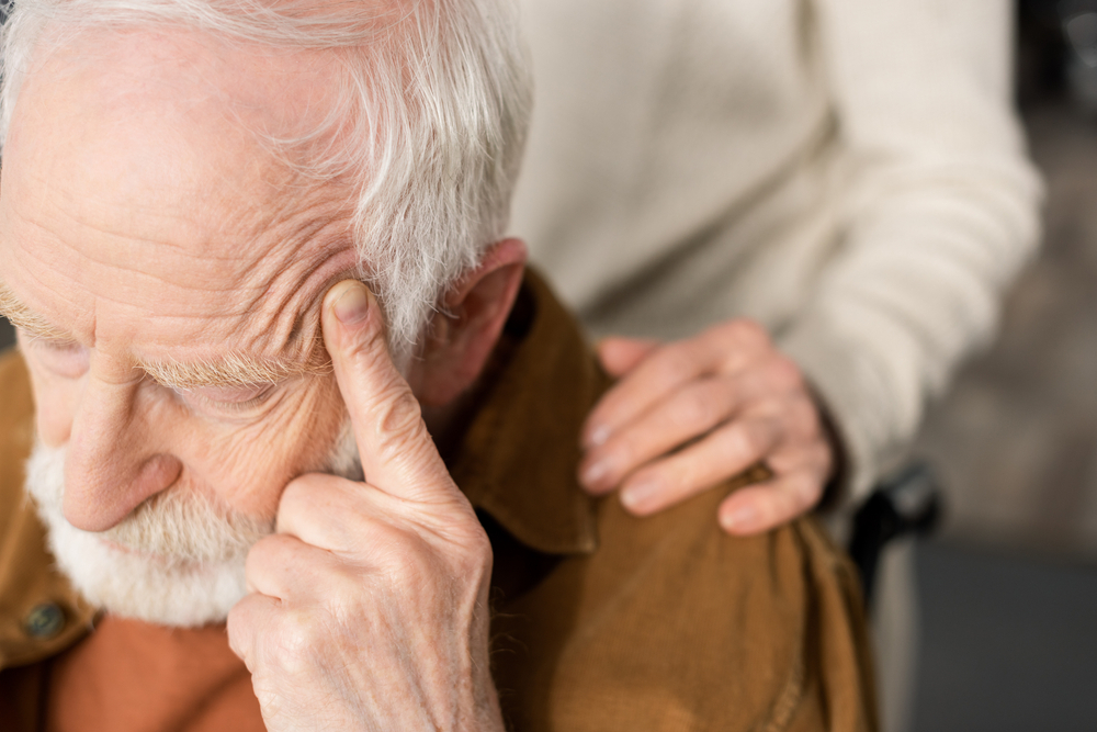 A senior man sits in a wheel chair with a concerned look on his face