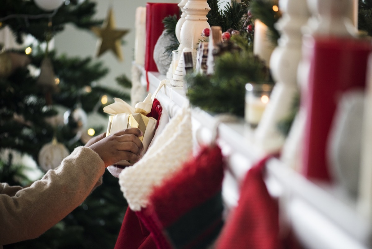 woman putting gifts in christmas stockings