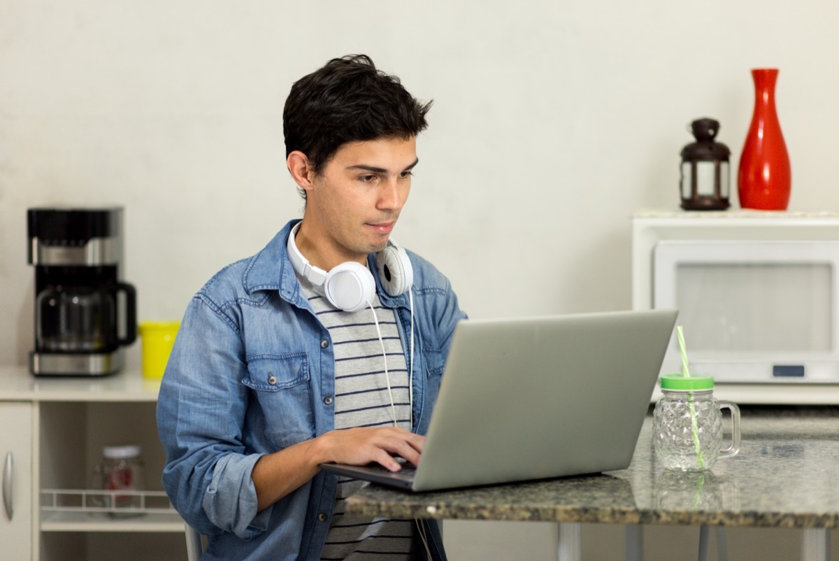 Man on his laptop with headphones at home