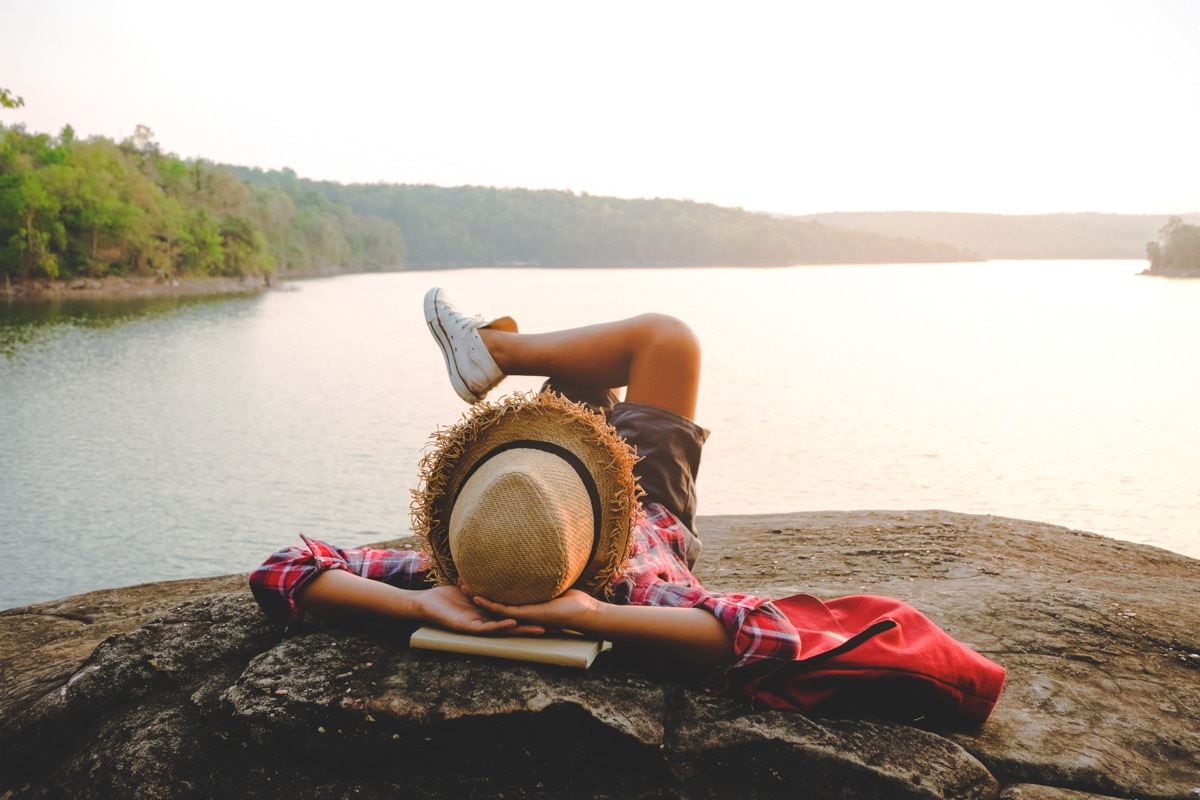 Person Laying on Rock by Water