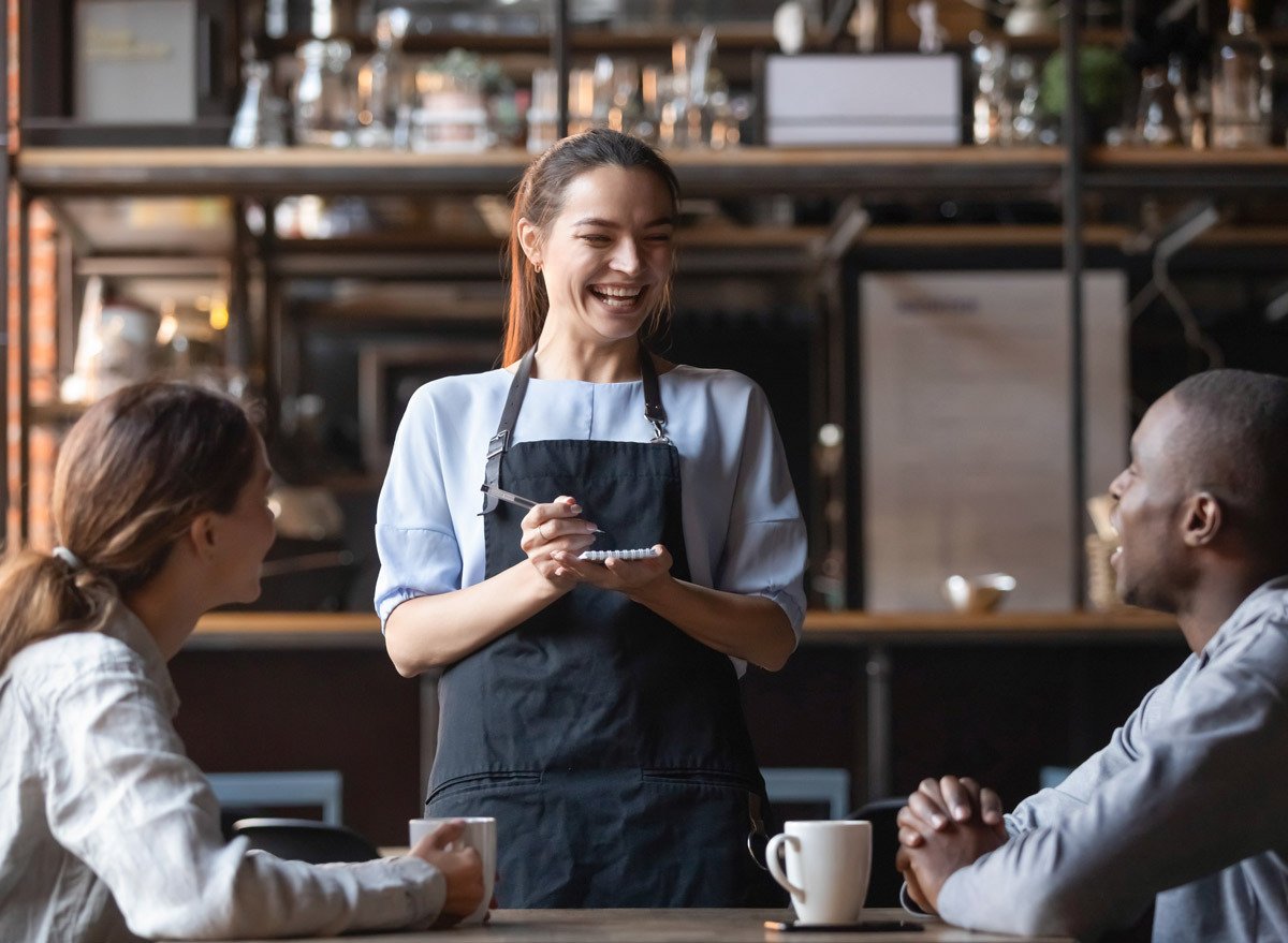 Waitress laughing with customer at a restaurant.