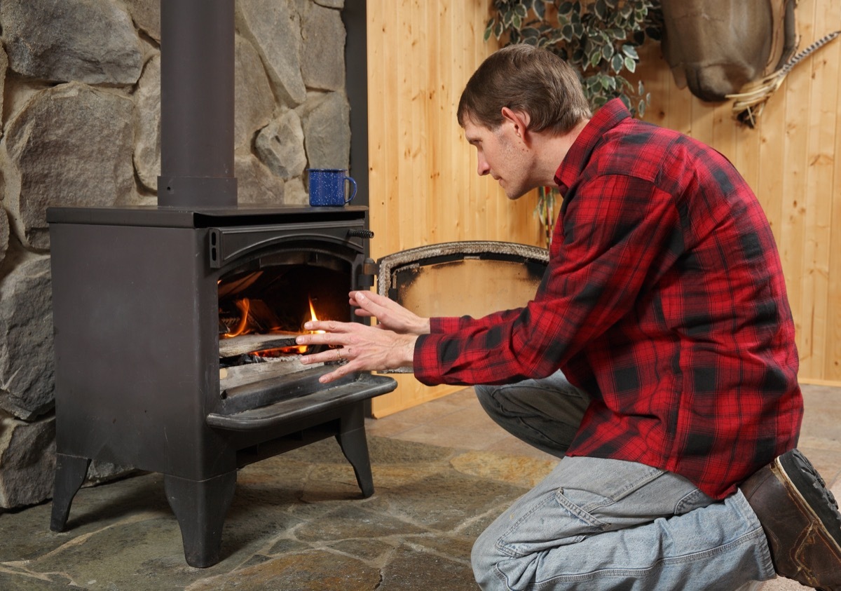 Man by the wood burning fire in a cabin