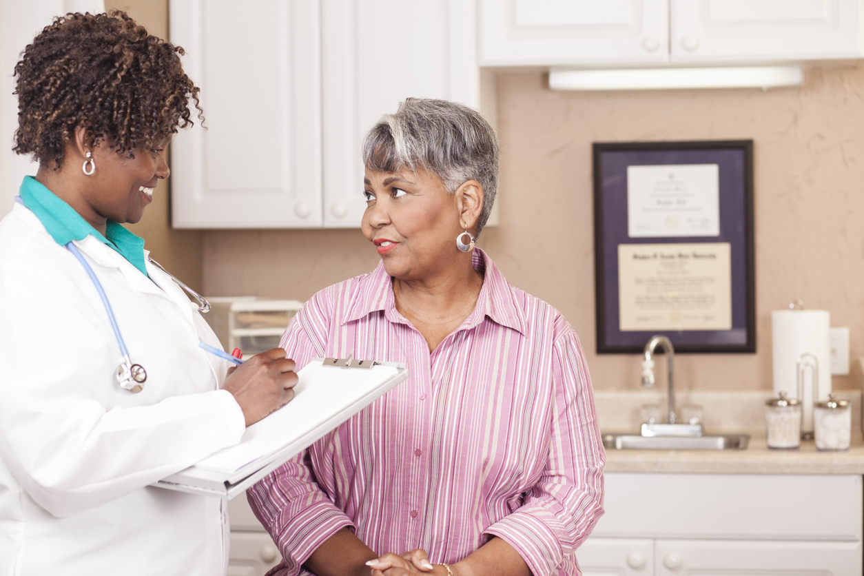 Doctor conducts medical consultation with senior adult patient at clinic.