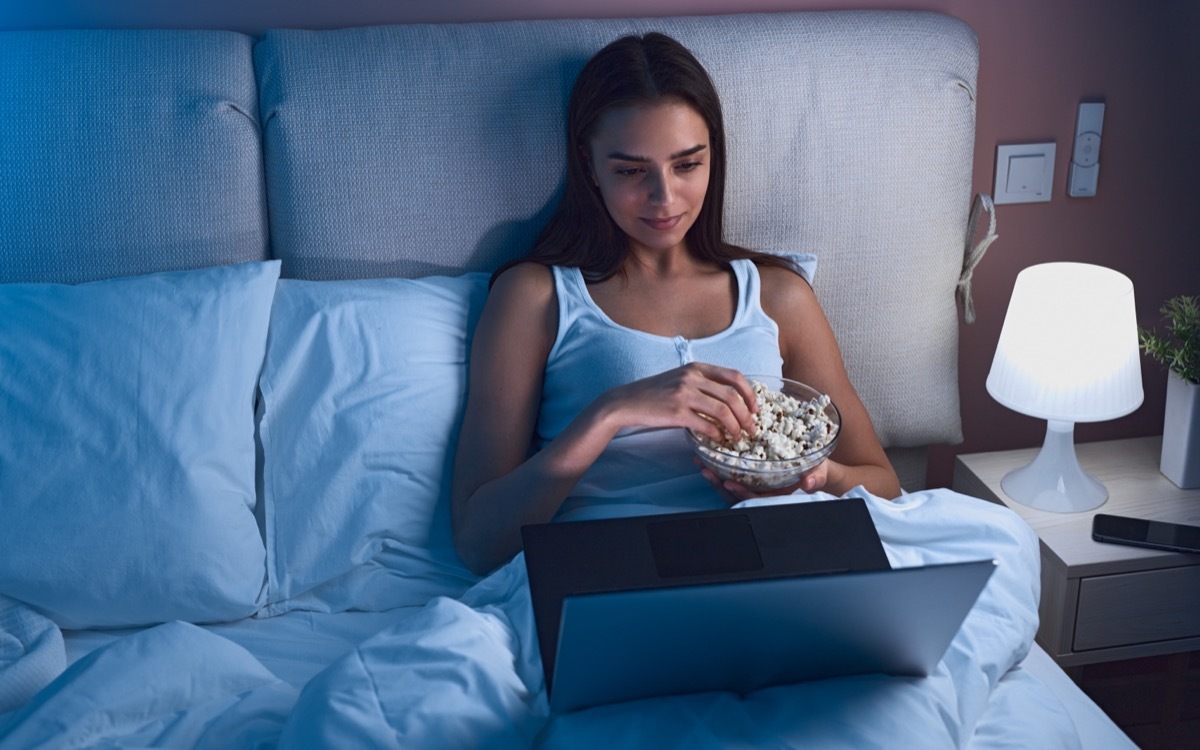 Woman Eating Popcorn in Bed