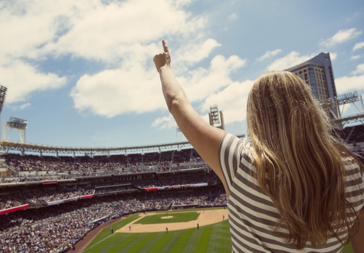 Woman standing and cheering at a baseball game