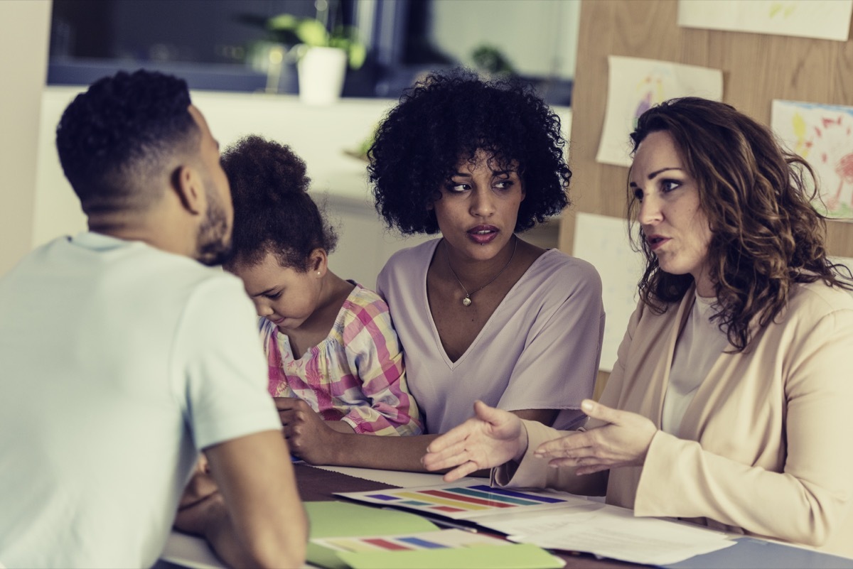 family talking with their young daughter's teacher looking serious and worried