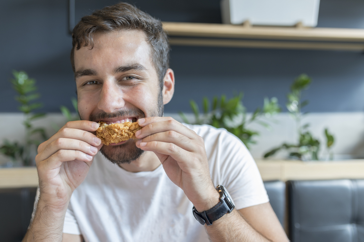 Young adult having a lunch break at the restaurant, eating chicken wings