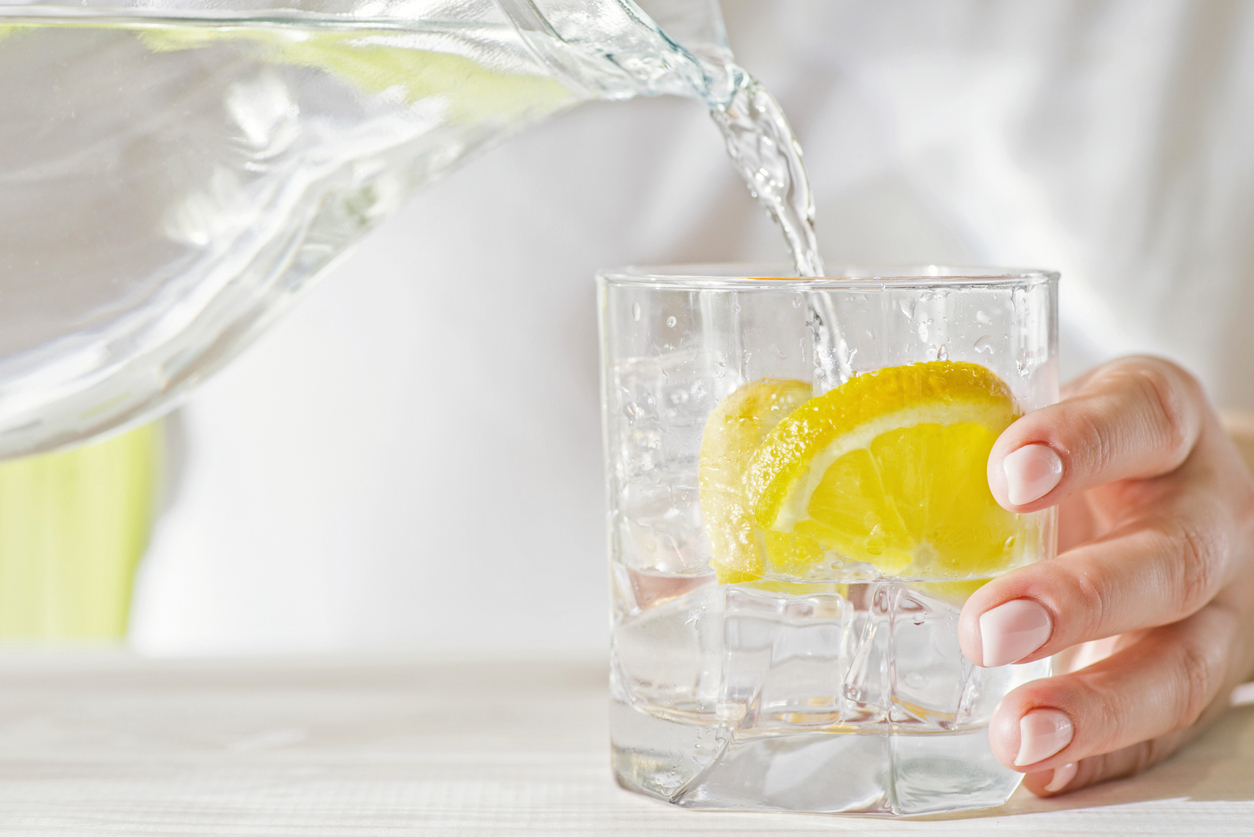 Water being poured into glass with lemon in it.