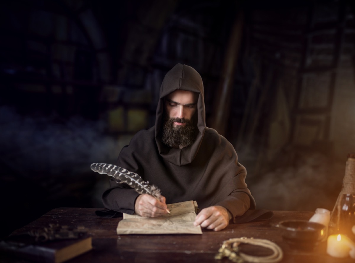 medieval monk writing on a scroll