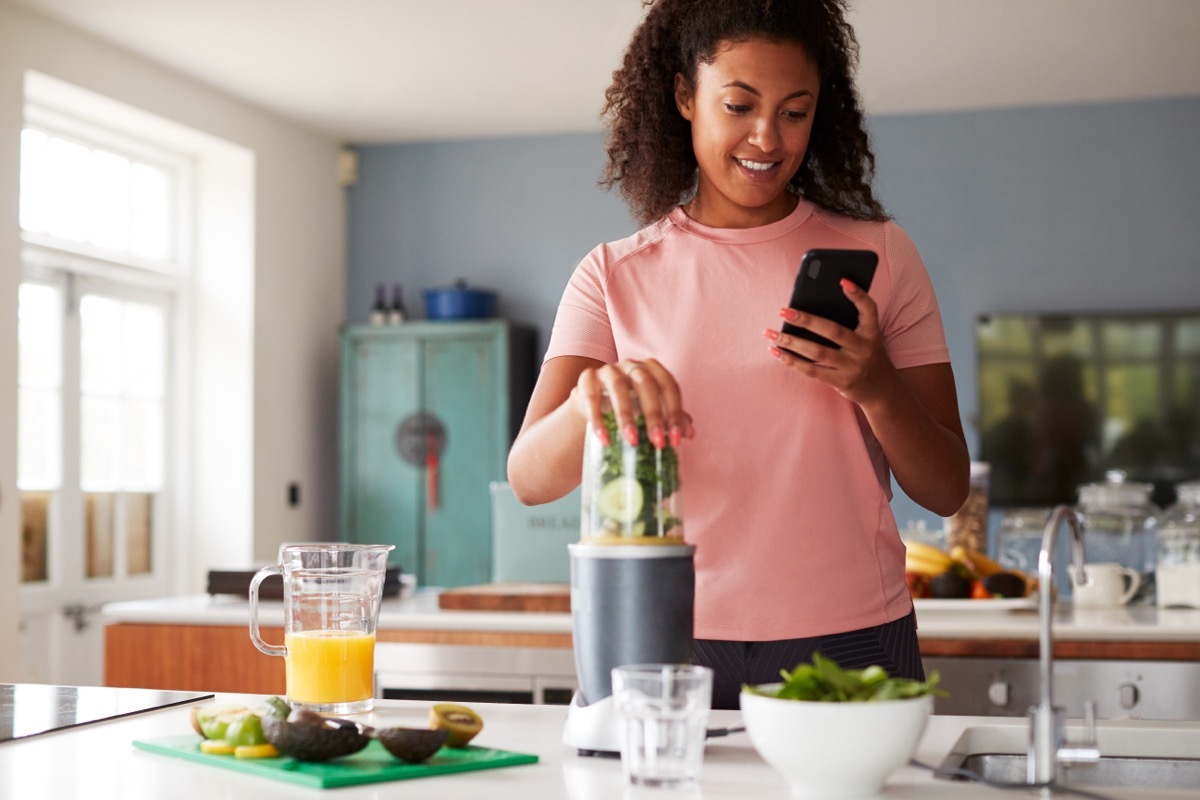 woman making healthy smoothie and tracking calories