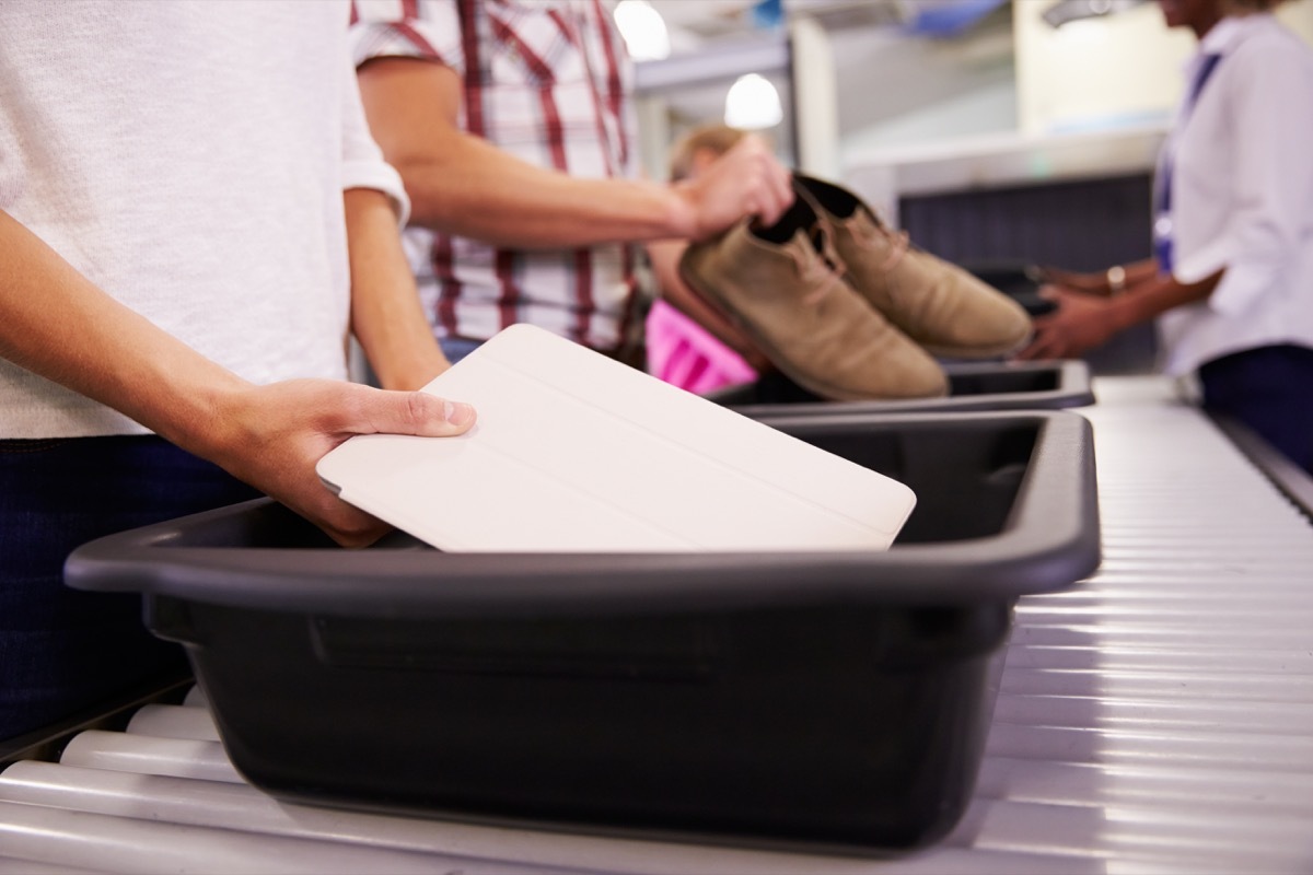 people putting their belongings into bins at the airport