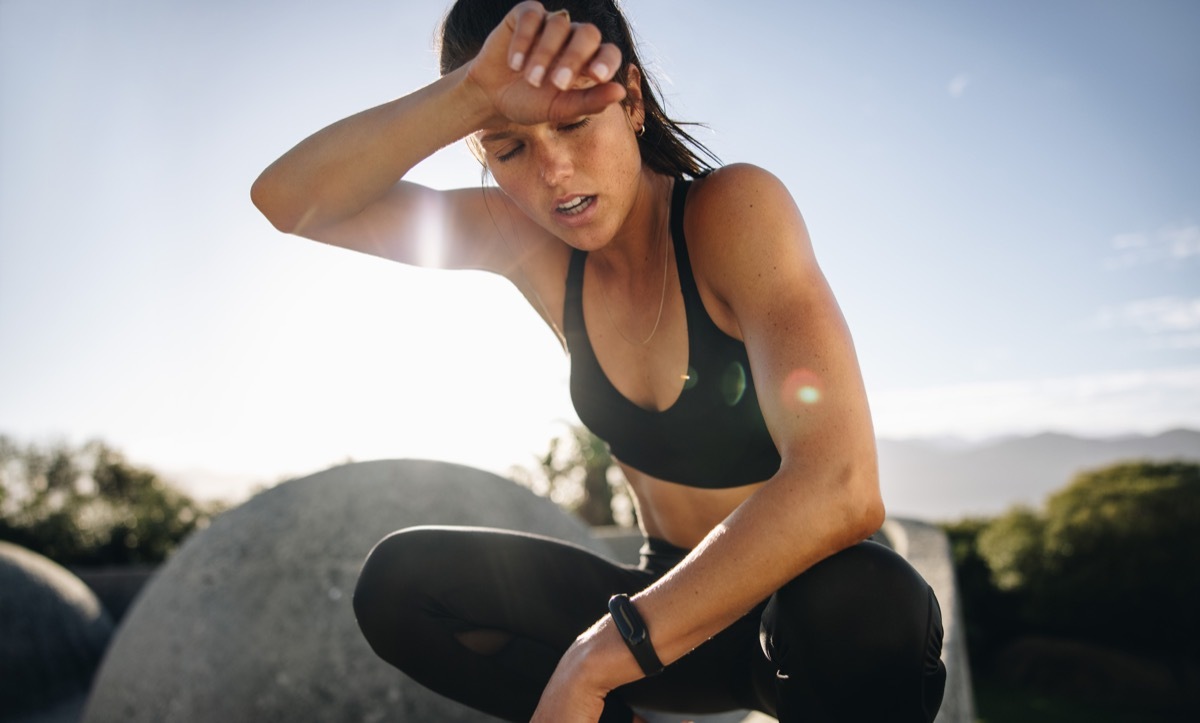 Sweaty woman sitting and resting in the sun after workout risking phytophotodermatitis