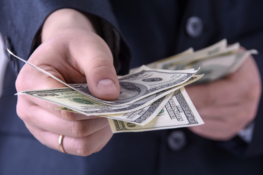 person's hands displaying one hundred dollar bills