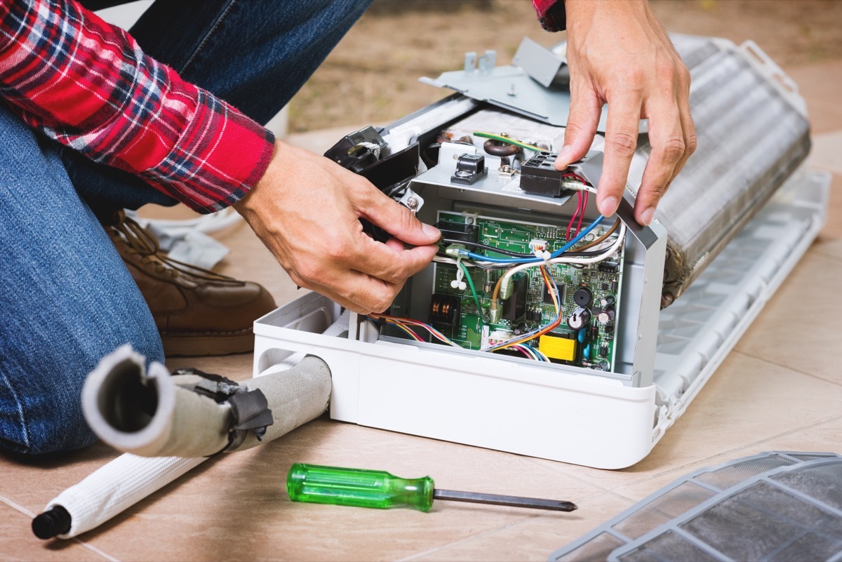 air conditioner tech repairing AC unit