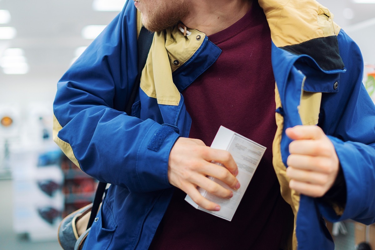 close up consumer thief's hands putting the new gadget in the pocket in the store