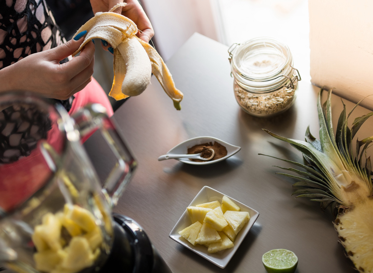 Woman peeling a banana to make a pineapple smoothie