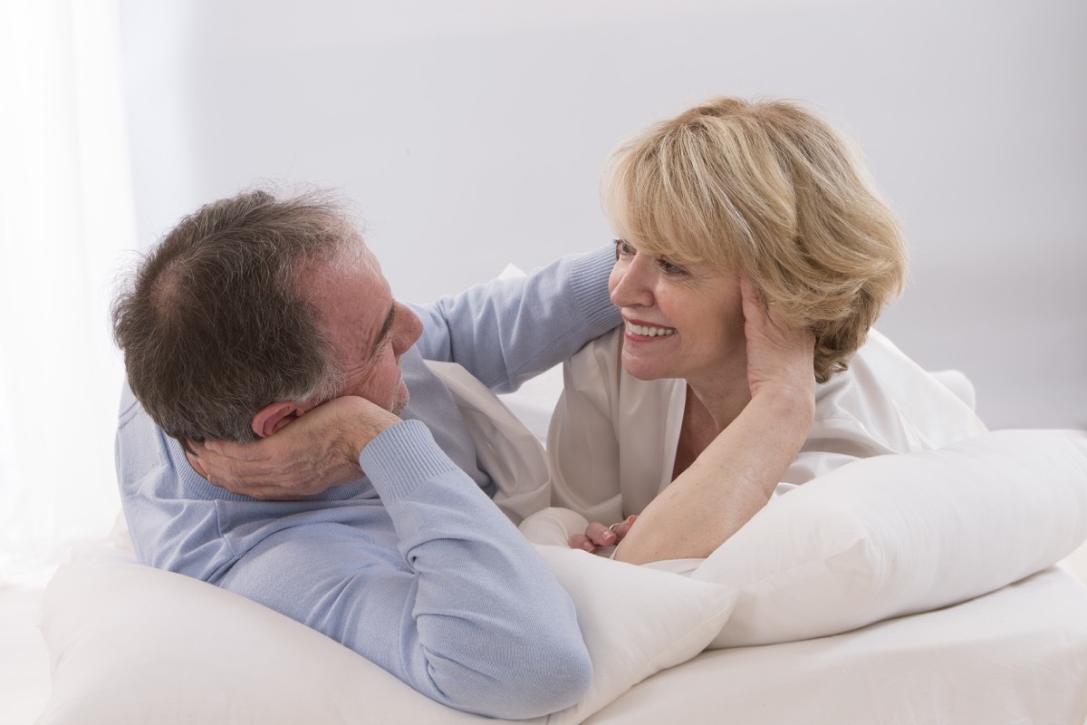 older couple smiling and happy together in bed, health questions after 50