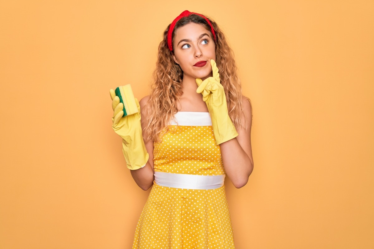 Woman in yellow dress with sponge and cleaning gloves