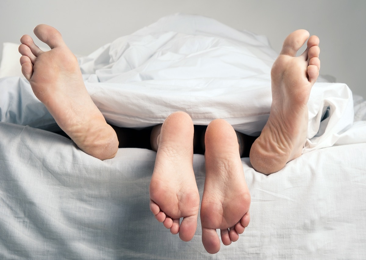 bare feet of a man and woman peeking out from underneath white sheets