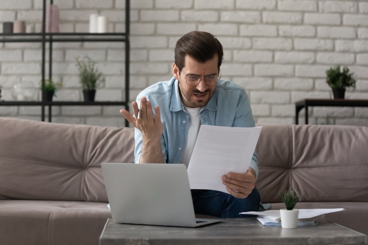 a man looks confused at a paper, computer