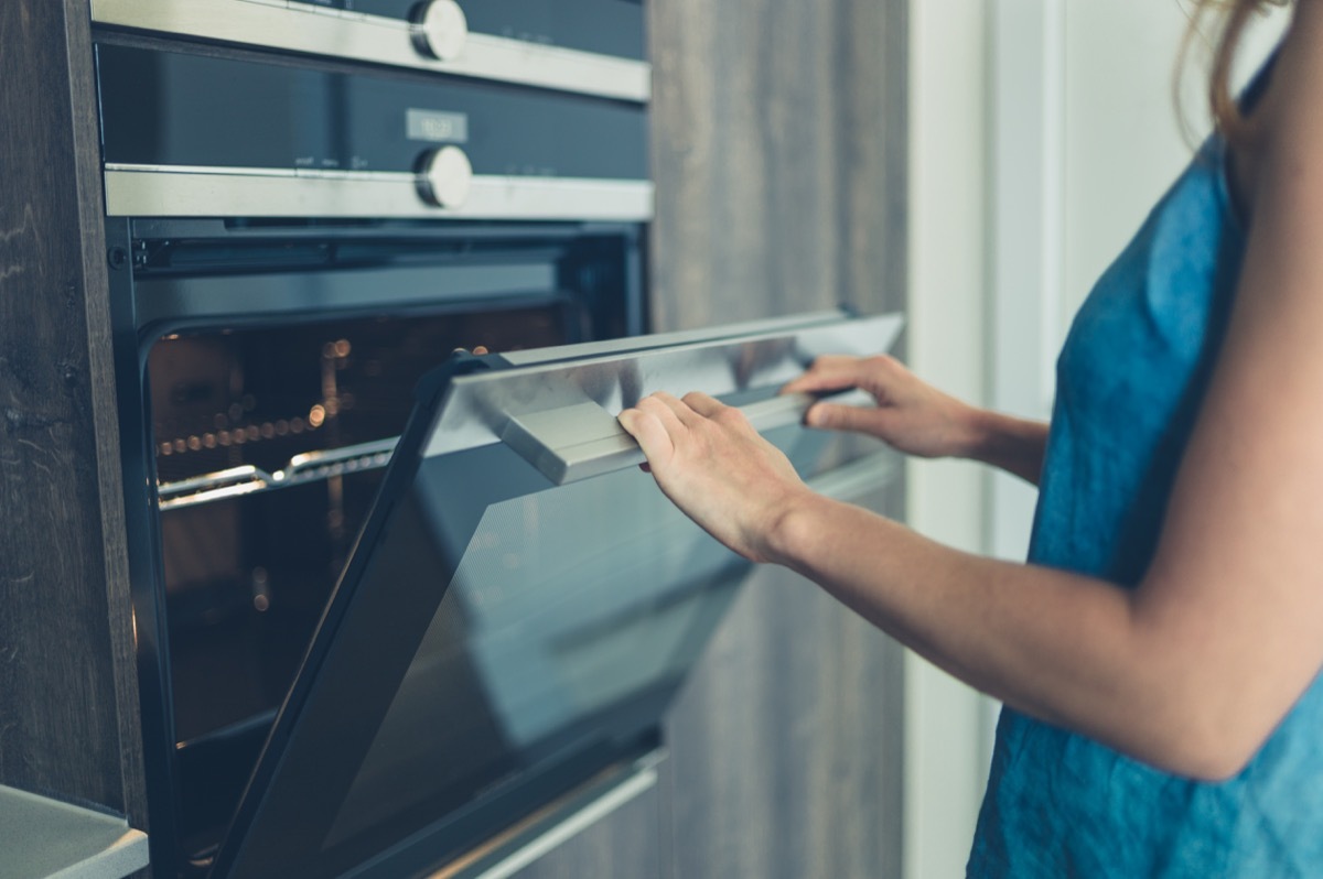 woman opening oven to possible use as a heater