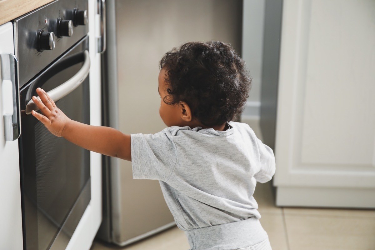 Baby near stove in kitchen. 