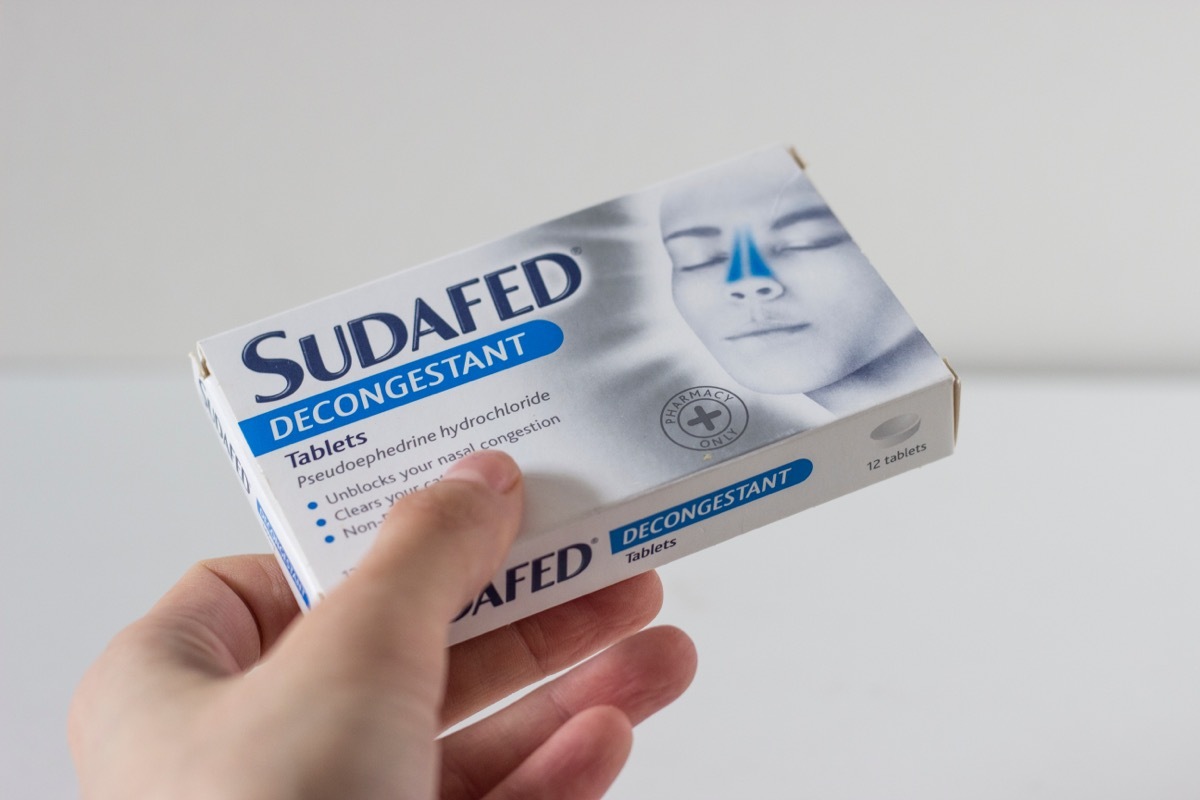 Hand holding box of sudafed decongestant