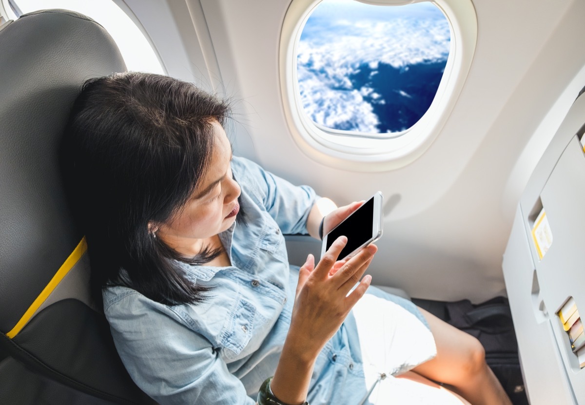 asian woman using her phone on the plane