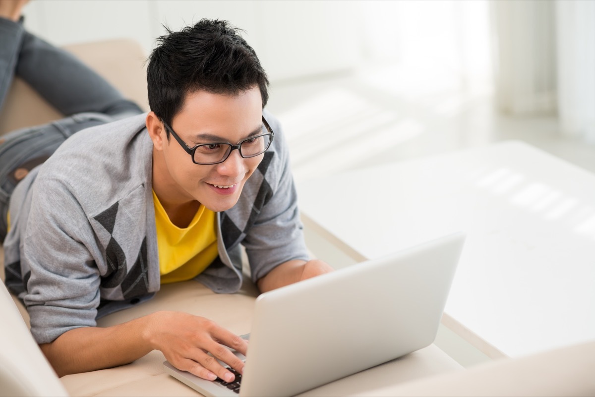 Happy asian man working from home on his laptop