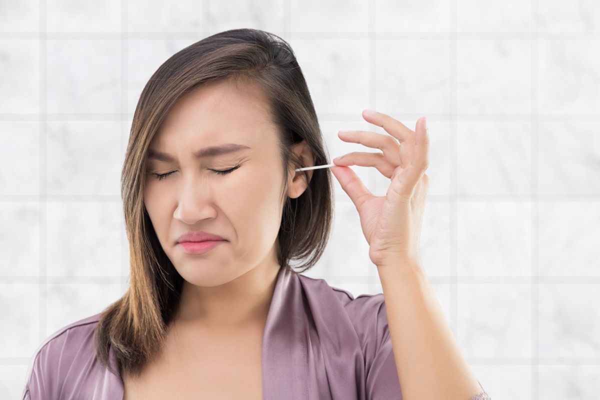 woman cleans ear with cotton swab