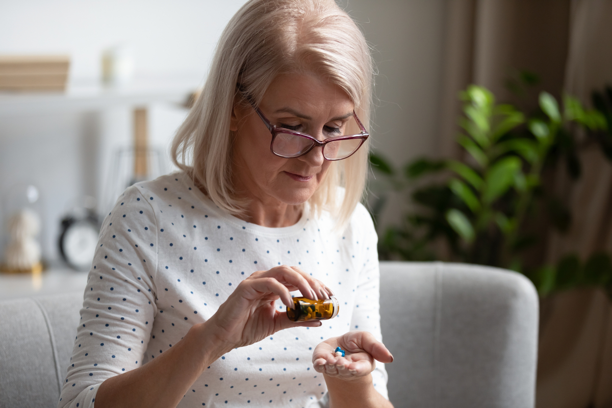 older white woman pouring pills into her hand