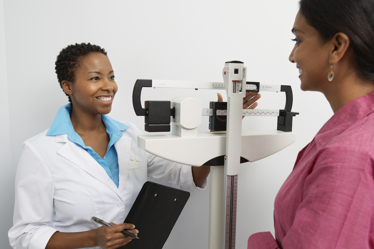 Woman being weighed by doctor