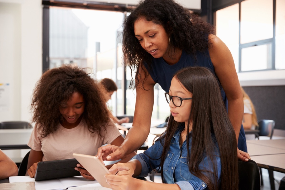 female teacher helping students in classroom, things you should never say to a teacher