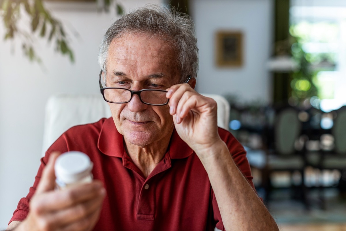 white-haired man reading supplement label