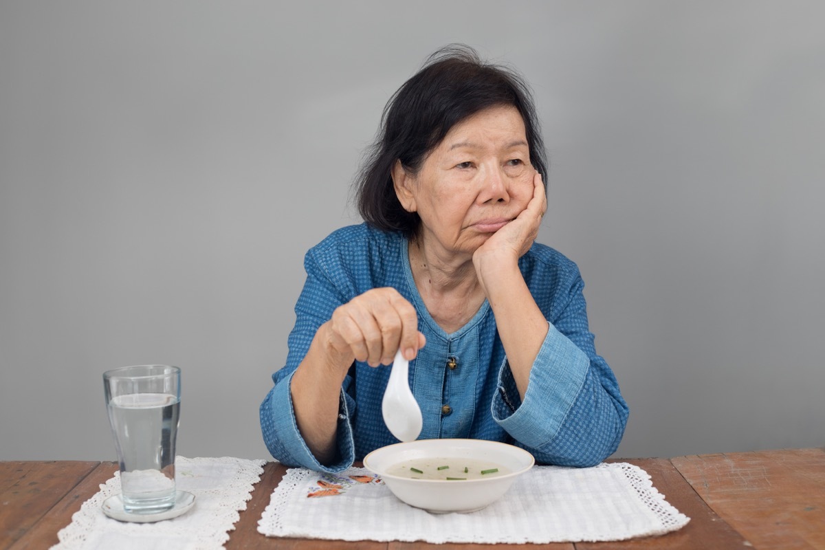 older asian woman refusing a bowl of soup