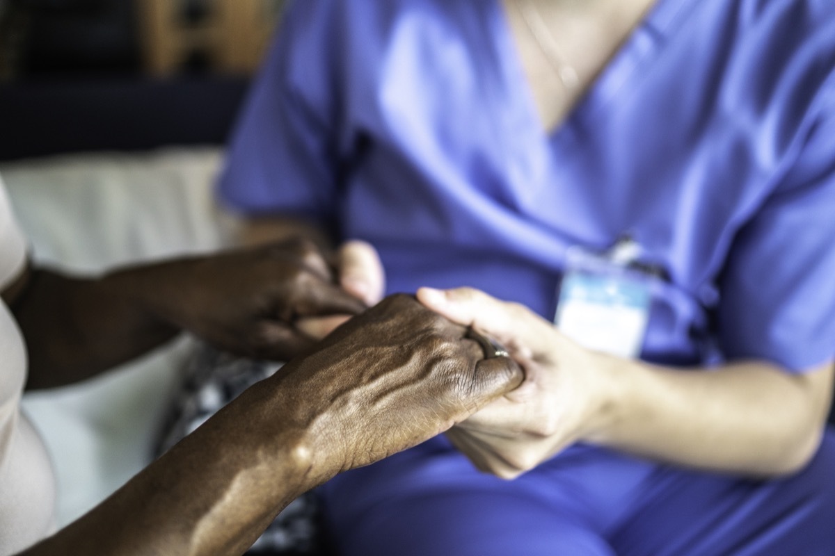 Close-up of home caregiver and senior woman holding hands