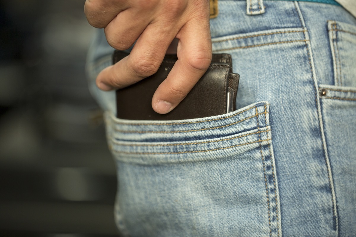 Man putting his wallet in his back pocket 